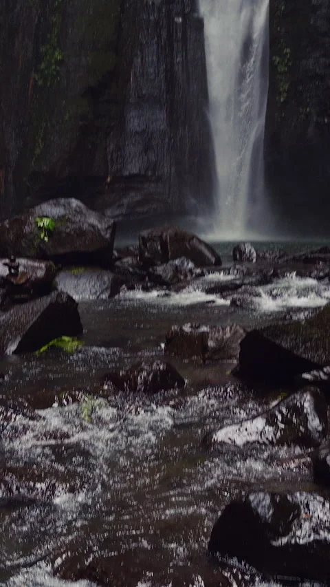 Vertical video. Wide Angle View of Hidden Waterfall Cascading Into Rocky Pool Su Stock Footage 337051914