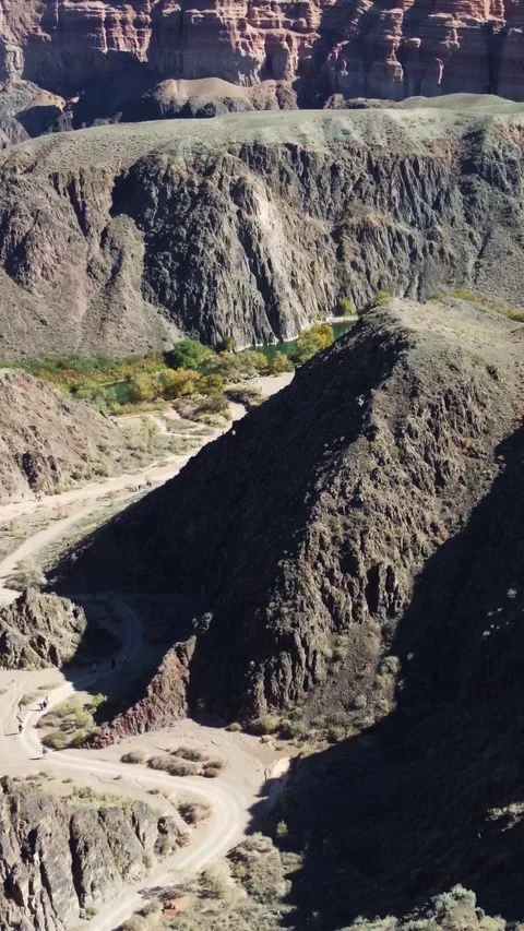 Vertical video: Winding dirt trail and hikers, Martian Charyn Canyon, Kazakhstan Stock Footage 336692599