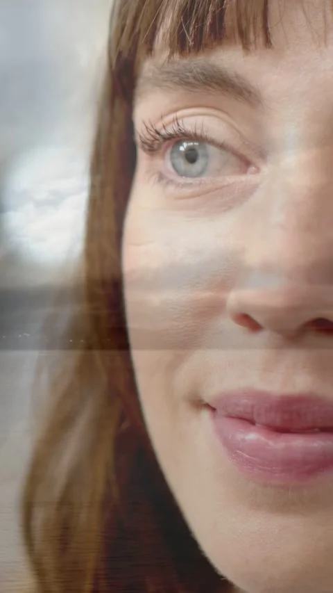 Vertical video: Woman blinking, causing smile by window as streaks crossing face Stock Footage 333596510