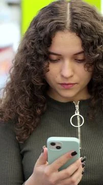 Vertical video. Woman checking to-do list on smartphone in supermarket. Onlin Stock Photos