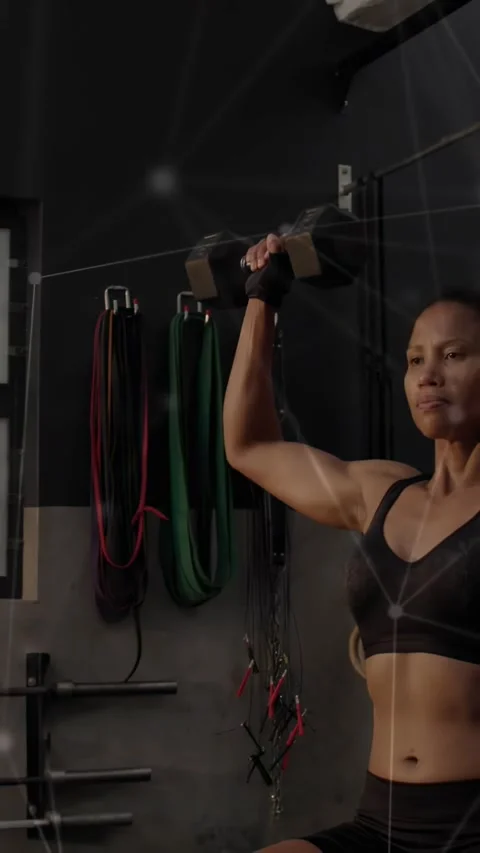 Vertical video: Woman doing right DB press in gym from shoulder to train network Stock Footage 330982249