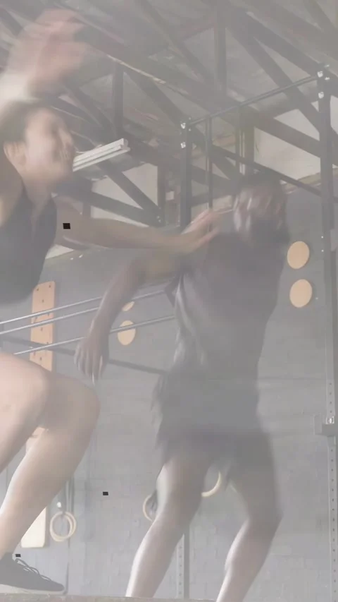 Vertical video: Woman doing squats and box jumps while man running into gym rig, Stock Footage 333157676