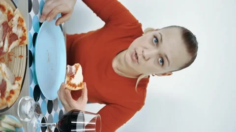 Vertical video, woman at home at the table eating pizza with his hands Stock Footage 150752353