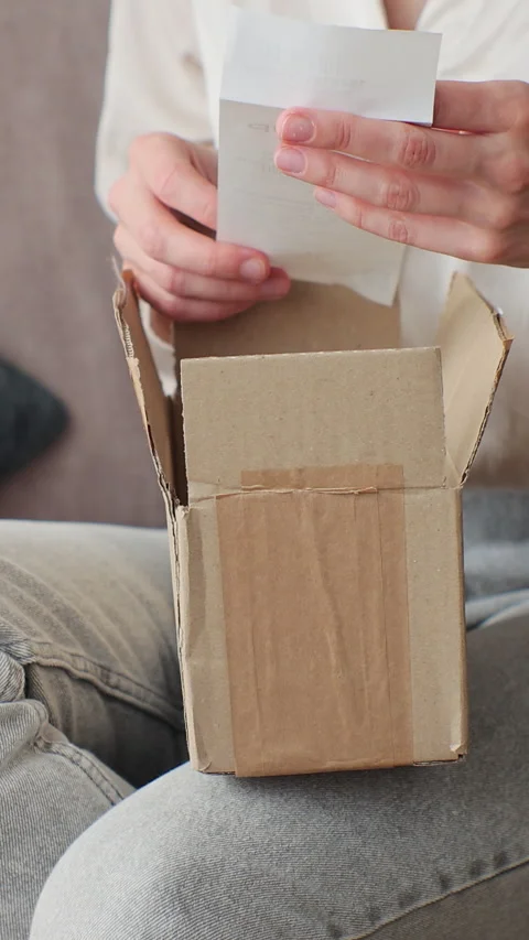 Vertical video. Woman opening package at home. Stock Footage 344878672
