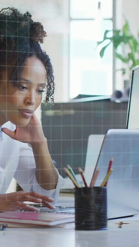 Vertical video: Woman pausing then typing on laptop, binary grid overlaying desk Stock Footage 333978341