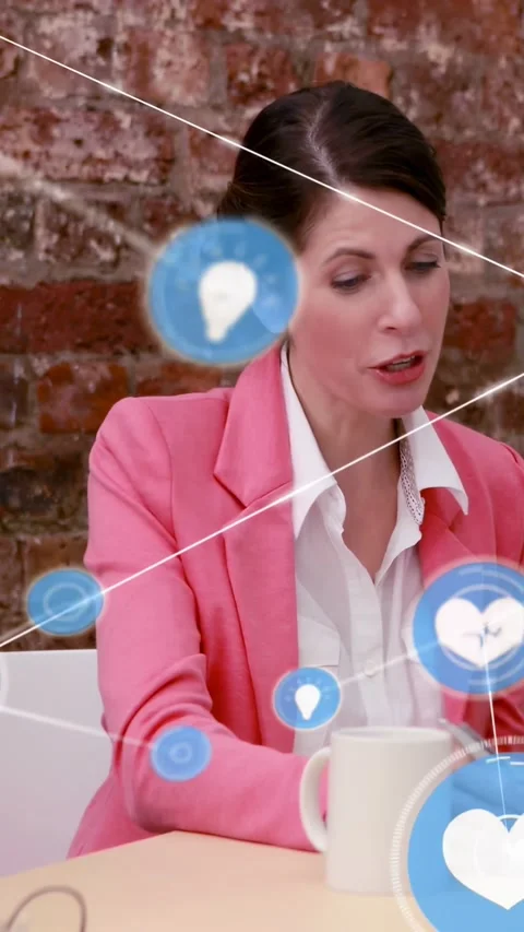 Vertical video: Woman at table moving hands by mug, making blue icons spread for Stock Footage 334319089