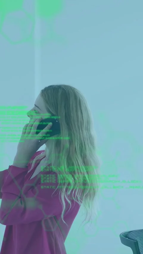 Vertical video: Woman taking notes during business call, green code flowing Stock Footage 333840168