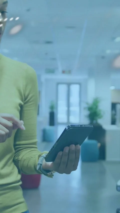 Vertical video: Woman tapping phone in tech office starting map, code overlay Stock Footage 331128564