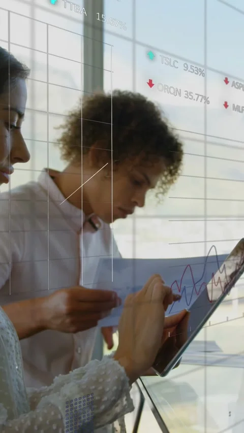 Vertical video: Woman tapping tablet while man comparing pages, finance charts Stock Footage 333465412