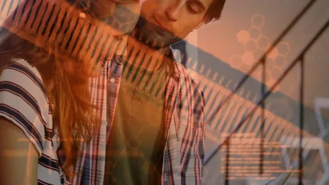 Vertical video: Woman tapping tablet, man leaning, orange data overlay rising, Stock Footage 334312490