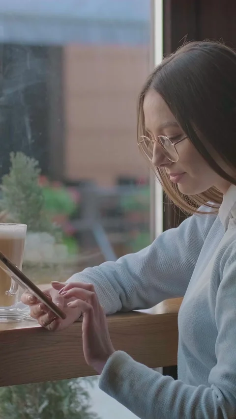 Vertical video. Woman using app on smartphone in cafe. Stock Footage 340979557