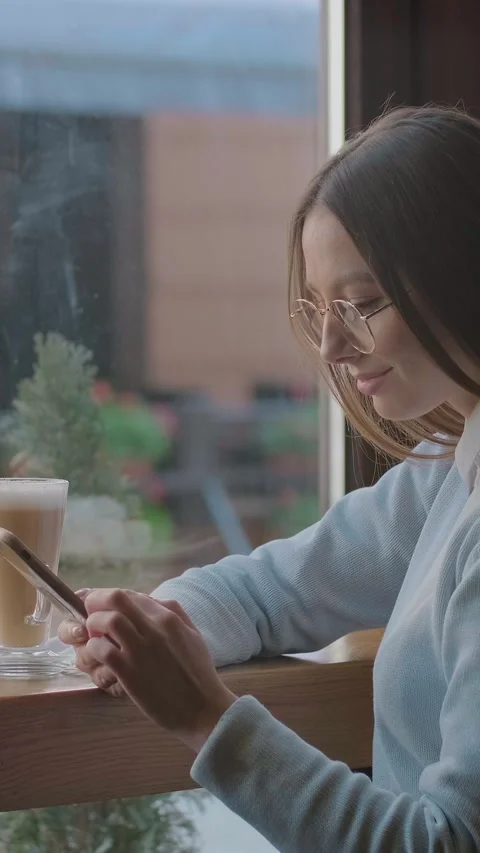 Vertical video. Woman using app on smartphone in cafe. Stock Footage 340984578