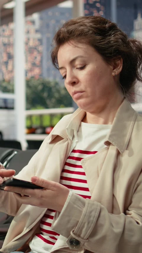 Vertical video Woman using notebook in bus terminal while listening to music in Stock Footage 341976708