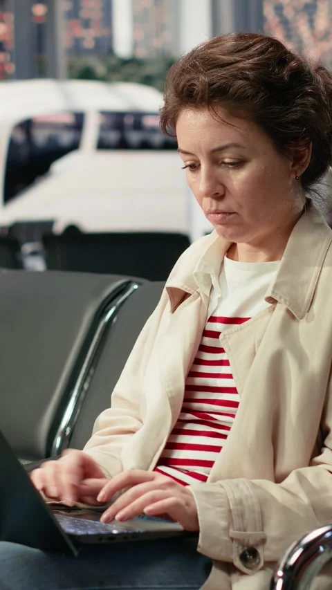 Vertical video Woman using notebook in bus terminal to check travel details Stock Footage 341978345