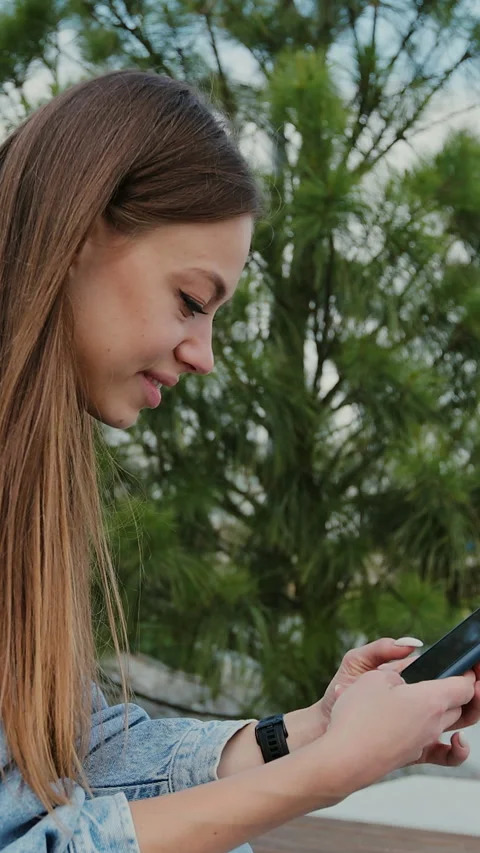 Vertical video. Woman using smartphone for online activities in modern city. Stock Footage 344685023