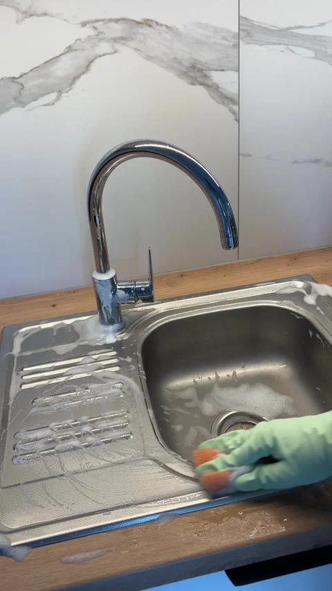 Vertical video of a womans hand in a rubber glove washing a metal kitchen sink Stock Footage 308930126
