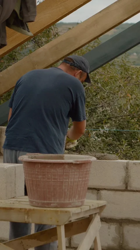 Vertical video Worker builds concrete brick wall for residential construction Video stock 327601679