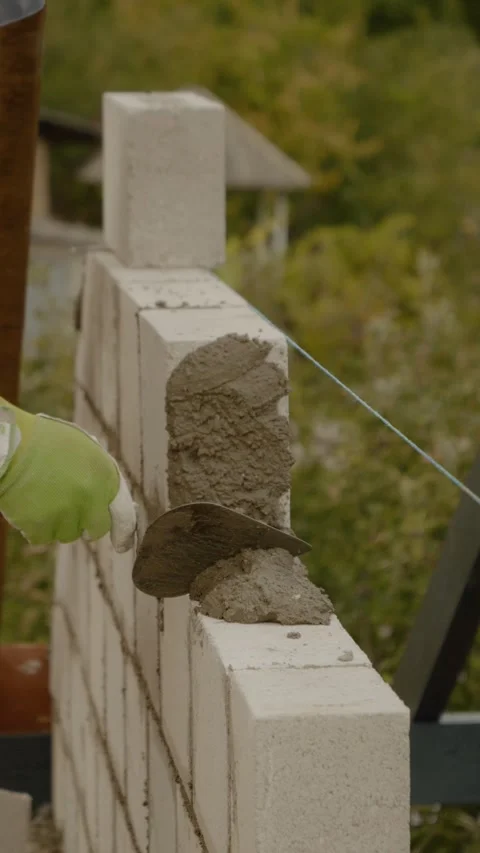 Vertical video Worker builds concrete wall while constructing a new house in a Video stock 327601748
