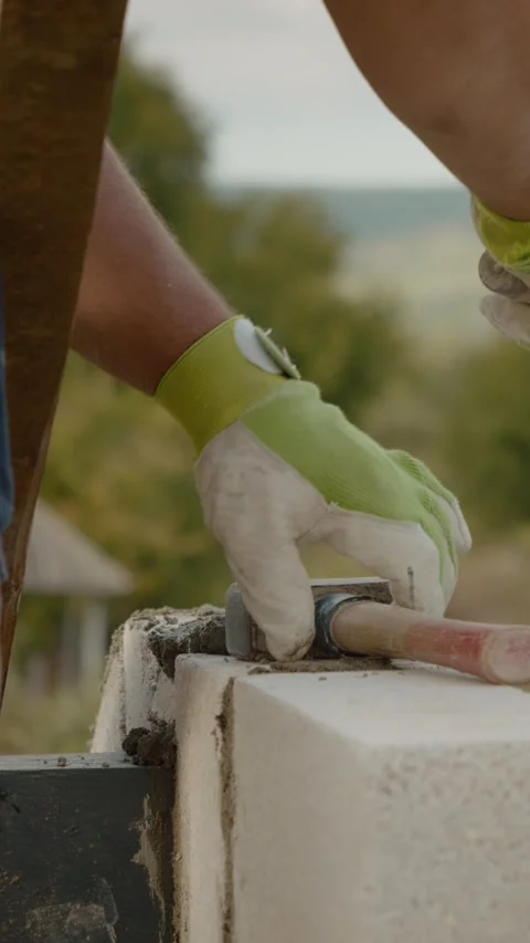 Vertical video Worker builds concrete wall with trowel in outdoor construction Video stock 327602096