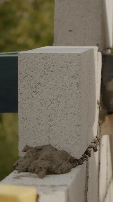 Vertical video Worker builds sturdy concrete wall with trowel at construction Video stock 327602152