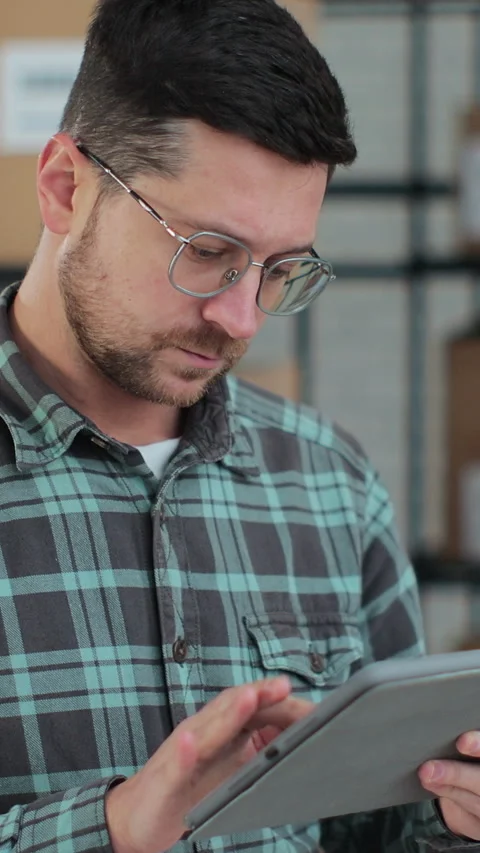 Vertical video. Worker checking inventory, writing notes on tablet. Stock Footage 345733331