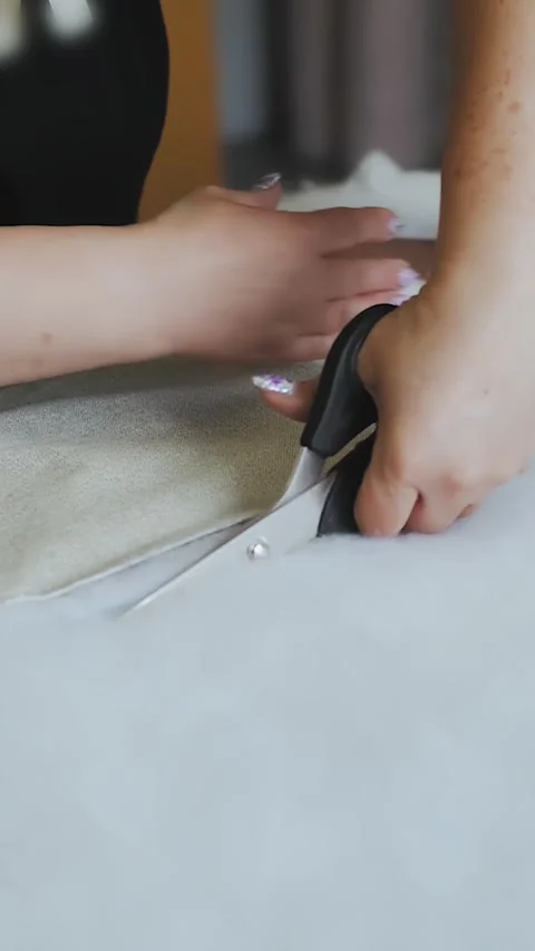 Vertical video. Worker cuts foam rubber with scissors lying on the table. The Stock Footage 323451356
