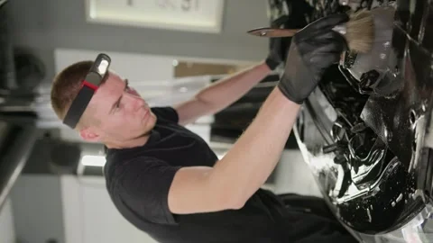Vertical video. A worker washes a car engine with a brush with soapy foam. Video stock 247543478