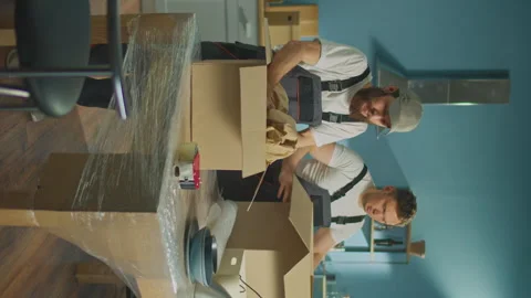 Vertical Video. Workers of Moving Company Carefully Packing Things at Boxes. Video stock 241385672