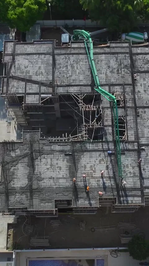 Vertical Video: Workers Pouring Concrete and Managing Structural Tasks at a Stock Footage 297792931