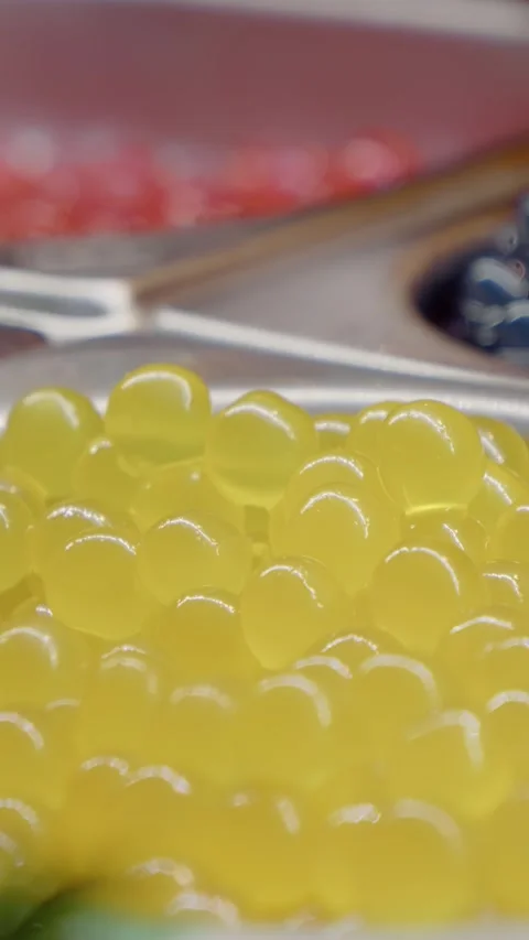 Vertical video Yellow tapioca pearls for bubble tea, with red and blue toppings Stock Footage 316486384