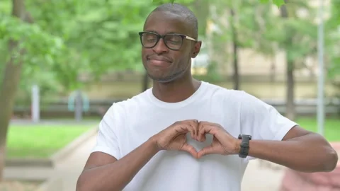 Vertical Video, Young African Man Making a Heart Gesture Outdoors Stock Footage 310832913