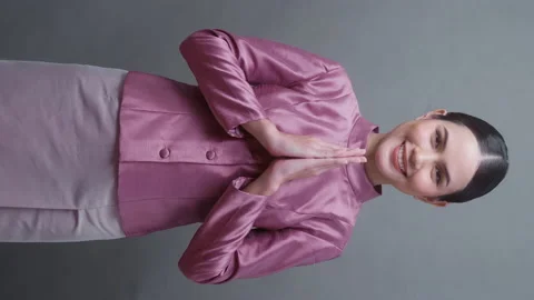 Vertical video. A young asian woman wearing Thai traditional cloth on gray .. Видео 233497053