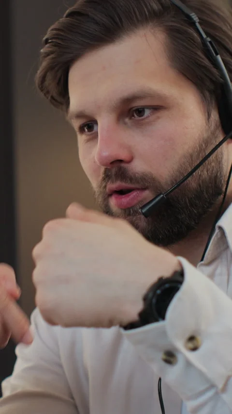 Vertical video. Young bearded man wears headset conference calling on laptop 库存影片 347779353