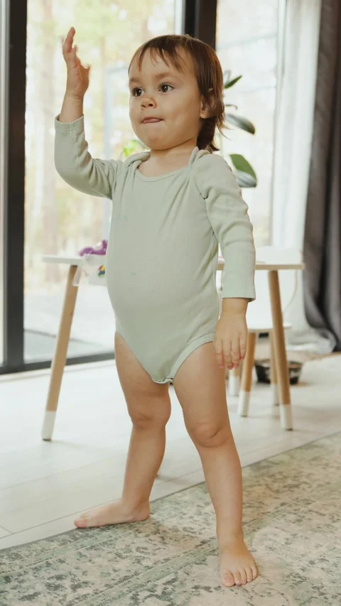 Vertical video. A young child joyfully dancing and playing with glee in a bright Stock Footage 311248271