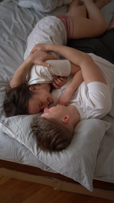 Vertical video, young couple on bed, girl on guy's shoulder, hugs, kisses, .. Stock Footage 267840805