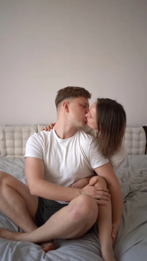 Premium Photo  Young couple in love man and woman are sitting by bed  hugging kissing in bedroom near christmas tree