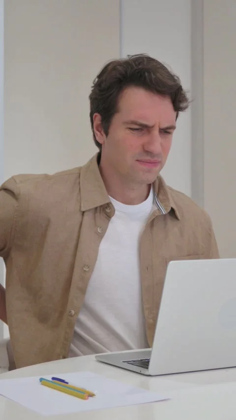 Vertical Video, Young Creative Man with Back Pain Typing on Laptop Stock Footage 318044634