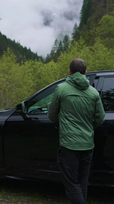 Vertical video of young handsome man getting inside sport SUV car in Swiss Alps Video stock 301547443