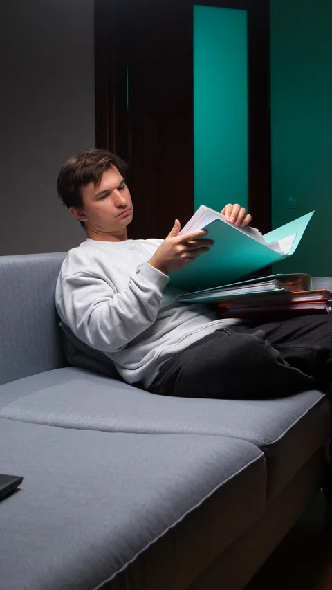 Vertical video young man analyzing important work documents and folders while Stock Footage 347237072