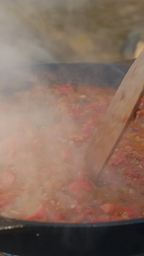 Vertical video of young man cooking cut tomatoes with red peppers Stock Footage 301365392