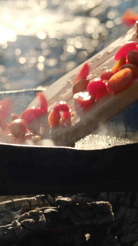 Vertical video of young man cooking red cherry tomatoes in frying pan Stock Footage 303958734