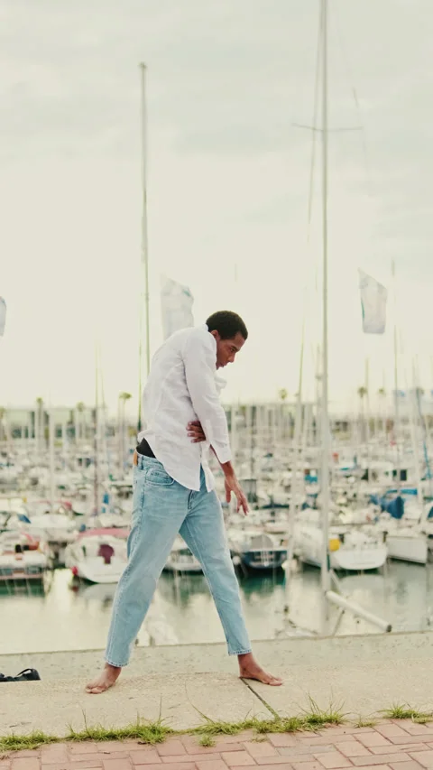 Vertical video, Young Man Dances Gracefully by the Marina Stock Footage 313813001