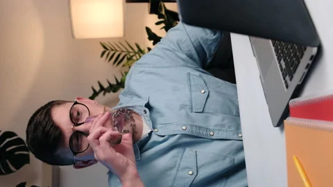 Vertical video of young man in eyeglasses working on laptop Stock Footage 234974499