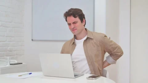 Vertical Video, Young Man having Back Pain while Working on Laptop Stock Footage 312914304