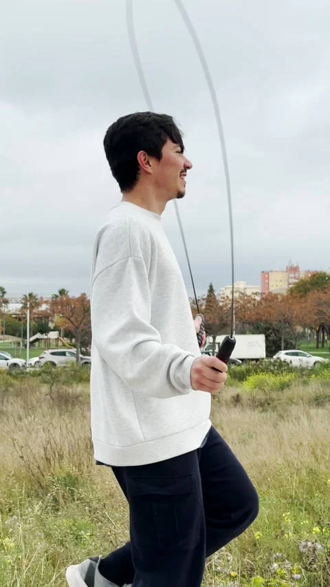 Vertical video of a young man jumping rope outdoors on a cloudy day Stock Footage 305155905