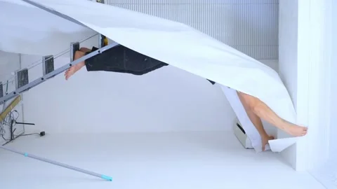 Vertical video. a young man in overalls glues wallpaper to the ceiling Stock-Footage 148337329