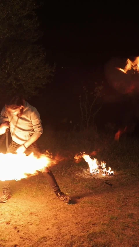 Vertical video. A young man performs a fire show. Swings a flame ball. Video stock 291253326