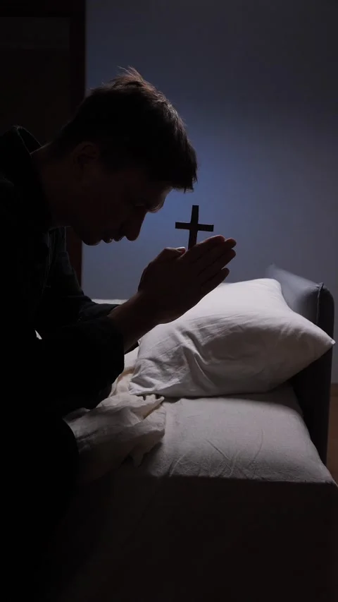 Vertical video Young man praying with wooden cross in bedroom Stock Footage 317253454