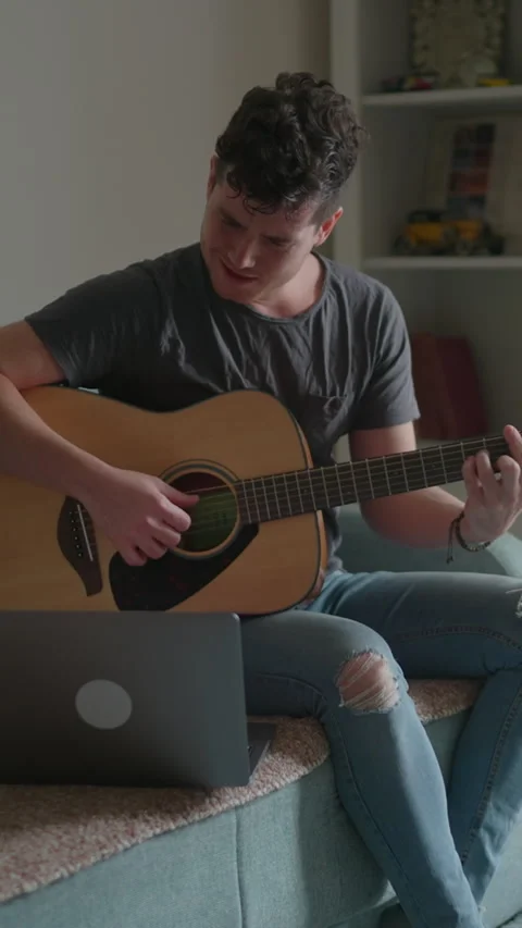 Vertical video: Young man is sitting with a guitar, a concert for advertising Stock Footage 298729752