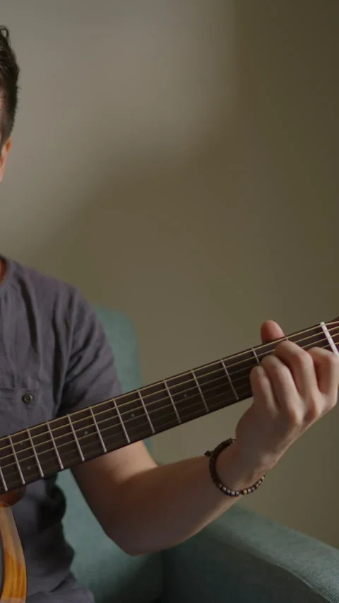 Vertical video: Young man is sitting with a guitar, a concert for advertising Stock Footage 298730517